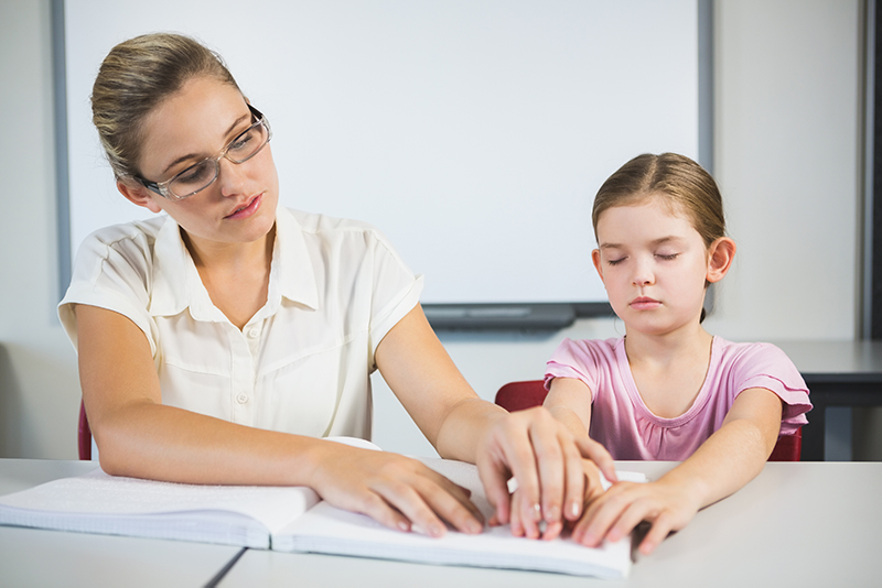 image of mother helping visually impaired daughter read braille
